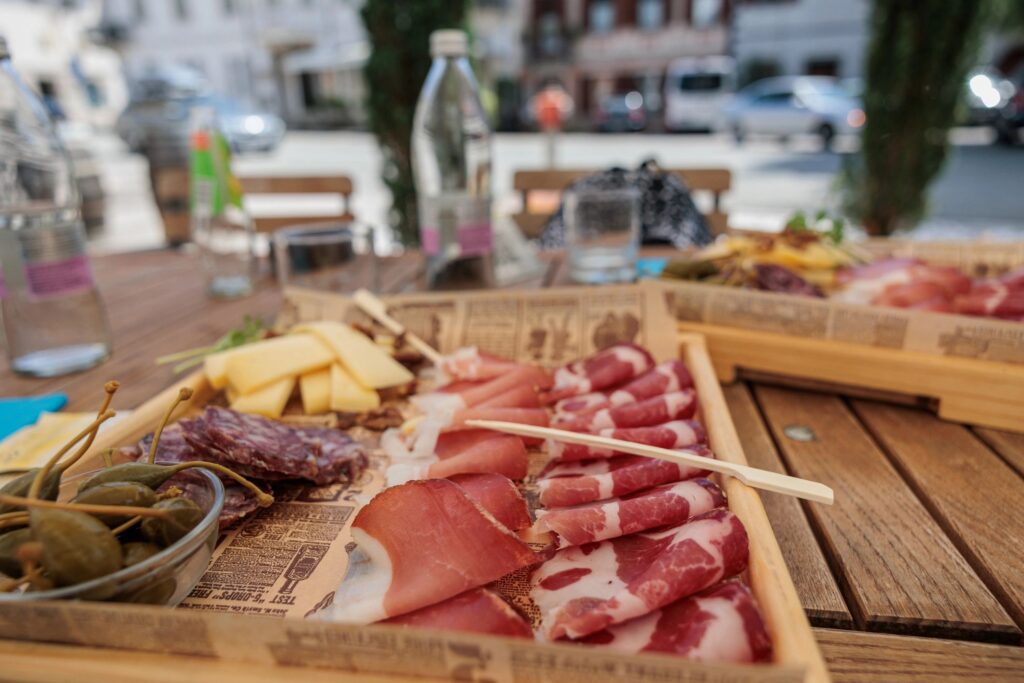 table set with a couple of wooden plates full of ham, salami and cheese slices at daytime at lunch