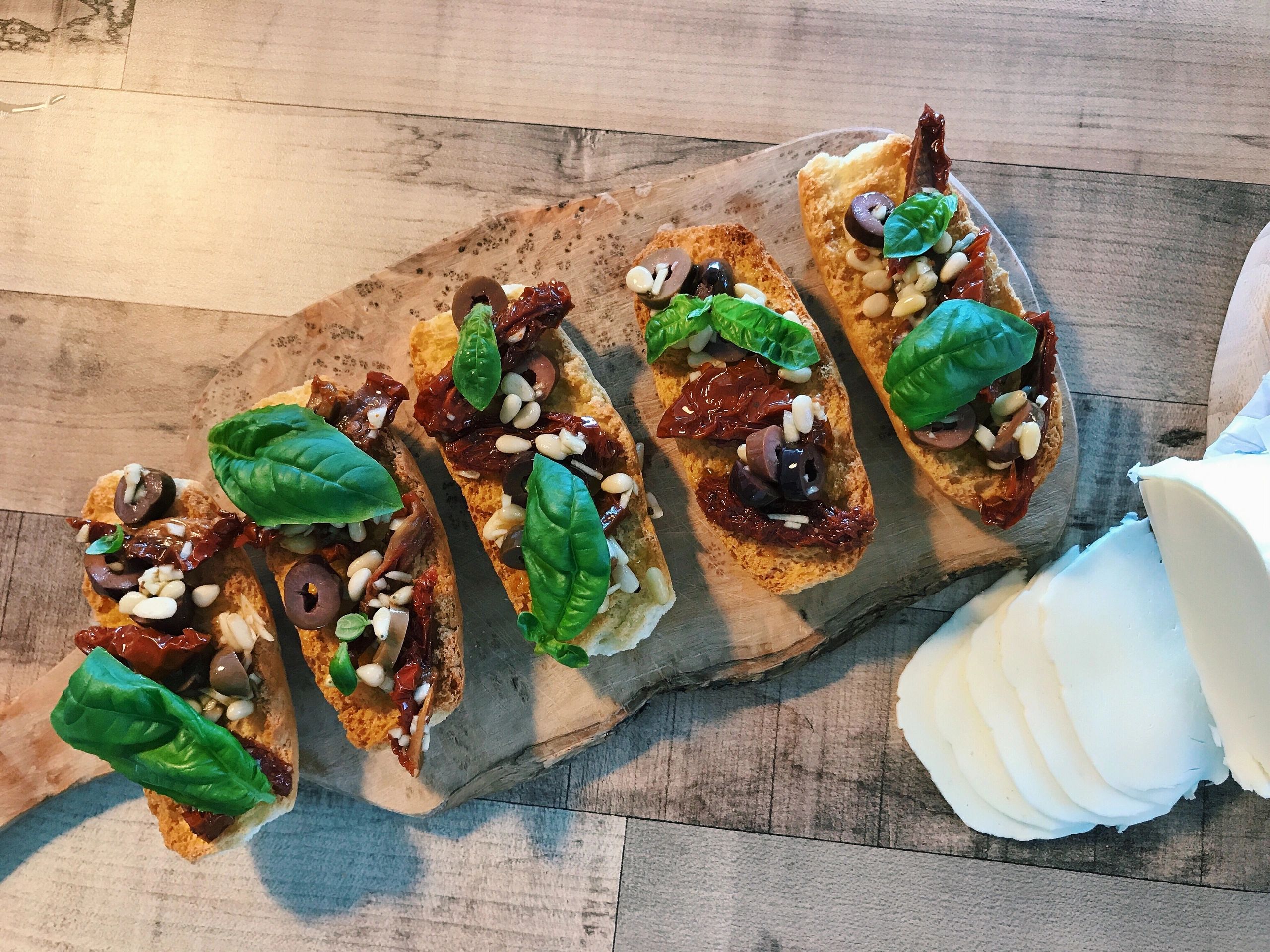 Bruschetta with basil, garlic, black olives, pine seeds, dried tomatoes and mozzarella cheese